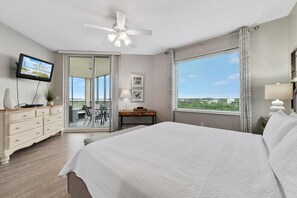 Ein Schlafzimmer mit einem großen Bett, einem Schreibtisch, einem Fernseher und einem Balkon mit Blick.