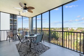 Ein Balkon mit Tisch und Stühlen, einem Deckenventilator und Blick auf eine Wohngegend.
