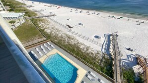 A beach view from a hotel balcony with a swimming pool, beach umbrellas, and lounge chairs. - Perdido Skye 65 (Pensacola)