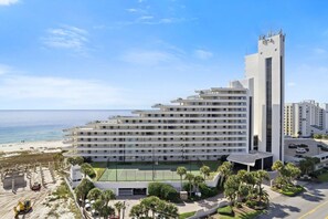 A multi-story hotel with a beach view, a tennis court, and a parking area. - Eden West 504 (Pensacola)