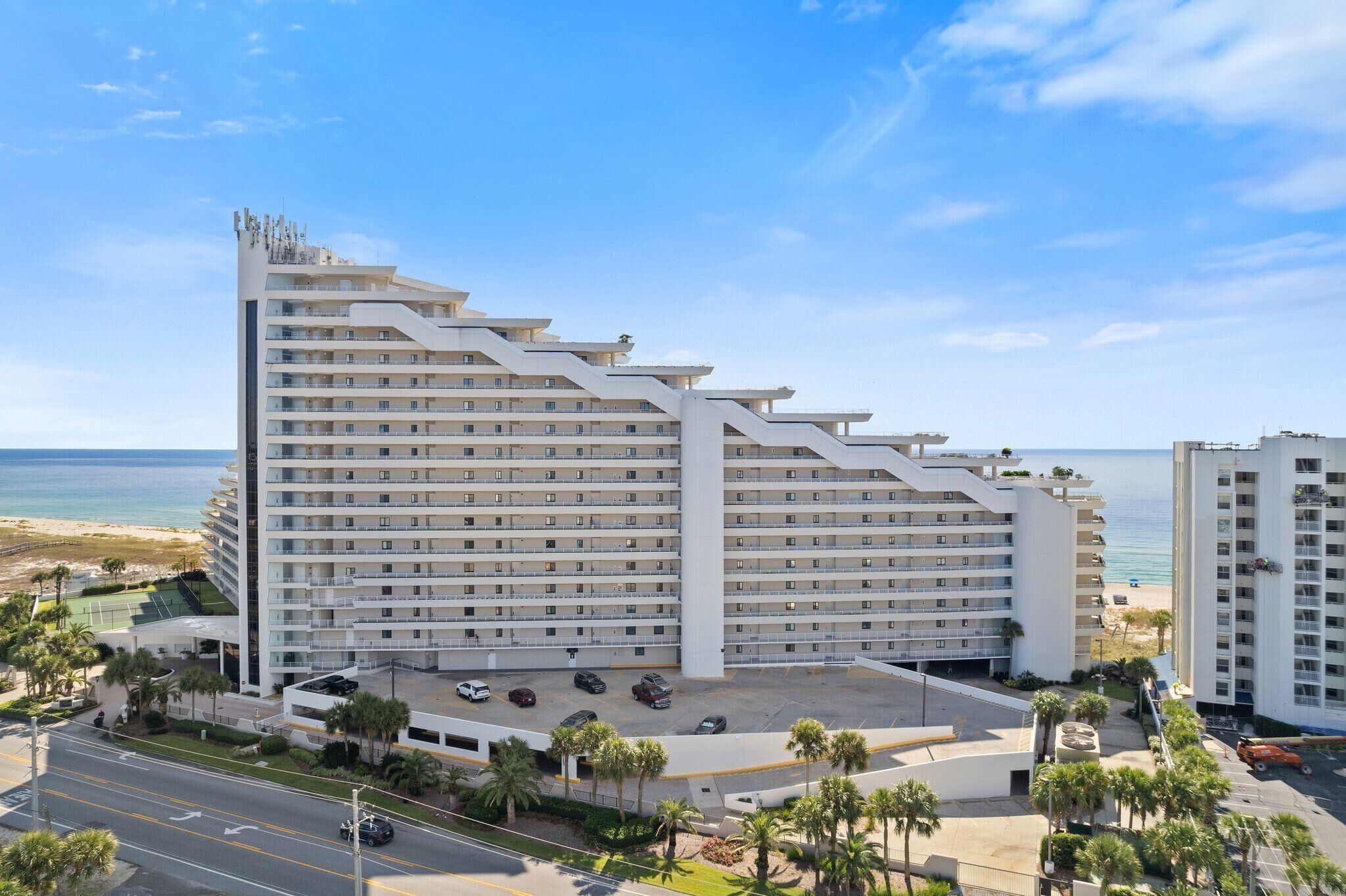 A multi-story hotel with a modern design, located near a beach with a clear view of the ocean.