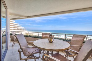 A balcony with wicker chairs and a round table, overlooking a beach and ocean. - Eden West 504 (Pensacola)