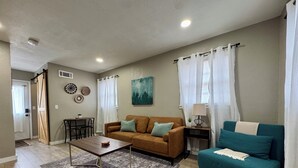 A living room with a brown sofa, a teal sofa, a wooden coffee table, and a patterned rug. - Near Wichita Airport! Pet Friendly W/ Fenced Patio (Wichita)