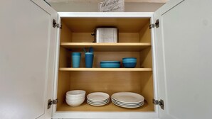 A kitchen cabinet with shelves containing bowls, plates, and a toaster. - Near Wichita Airport! Pet Friendly W/ Fenced Patio (Wichita)