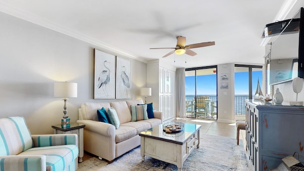 A living room with a sofa, armchair, coffee table, and a ceiling fan. - Phoenix VII 1002 (Orange Beach)