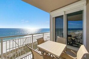 Enjoy the serene ocean view from this balcony with a table and wicker chairs.