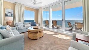 Un vaste balcon offrant une vue dégagée sur l’océan, aménagé avec un canapé, des fauteuils et une table.