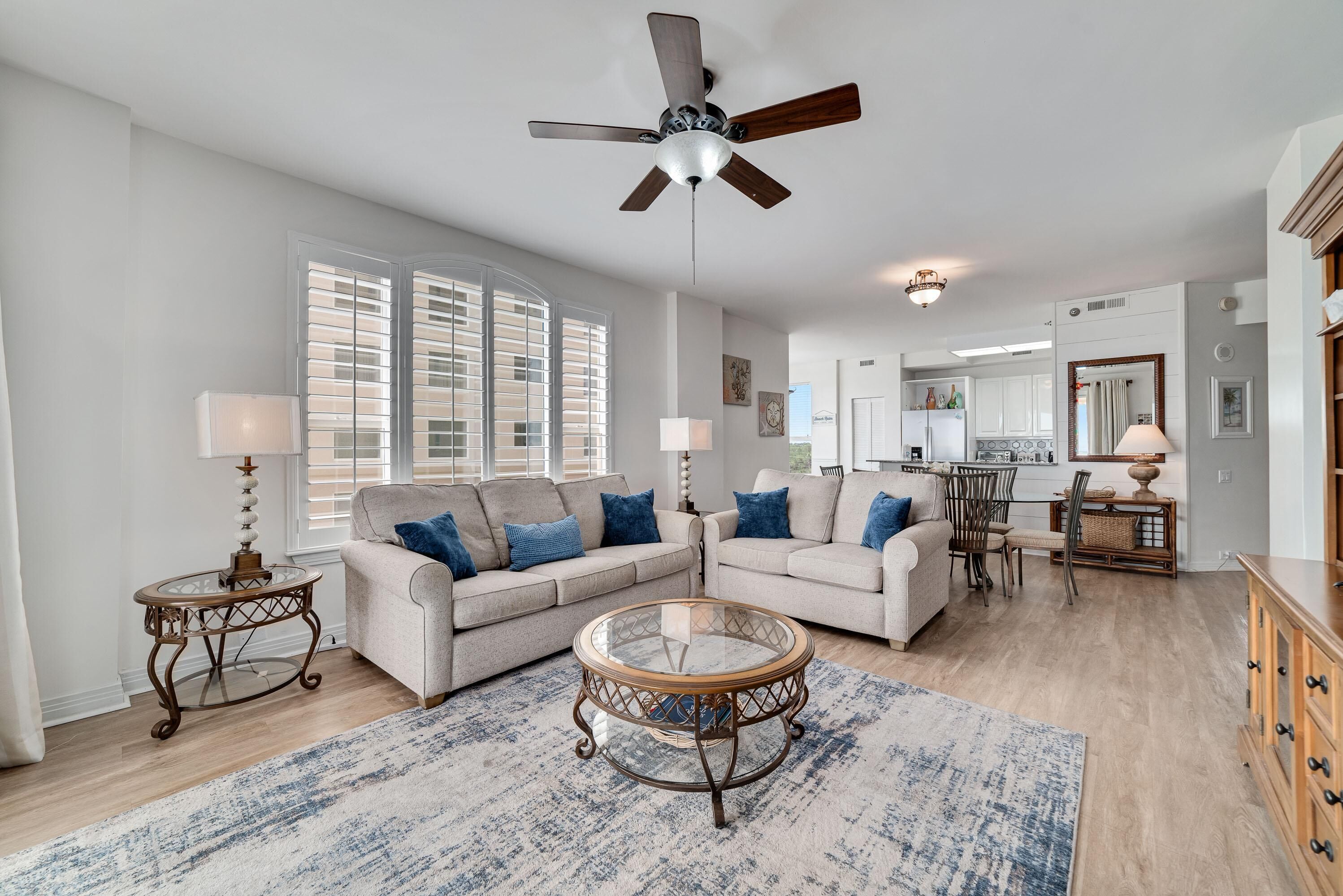 A spacious living room with two sofas, a coffee table, and a ceiling fan.