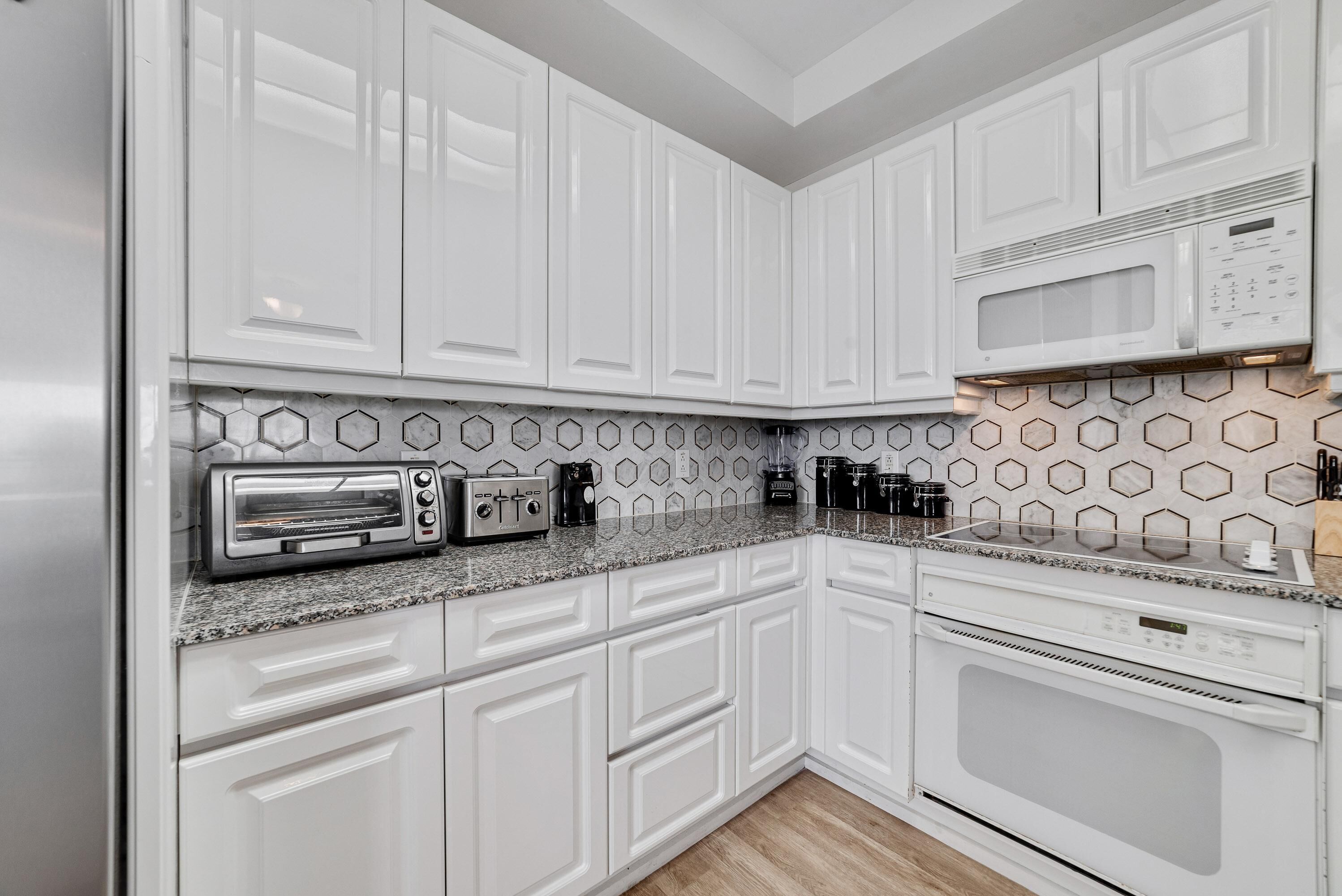 Una cocina moderna con armarios blancos, microondas, tostadora y cafetera.