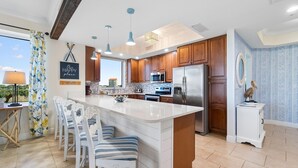 A modern kitchen with wooden cabinets, stainless steel appliances, and a central island with seating. - Lost Key A505 (Pensacola)