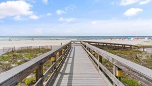 A wooden boardwalk leading to a beach with a clear sky. - Pelican Pointe 202 (Orange Beach)