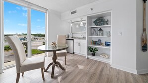 A modern kitchen with white cabinetry, a dining area with a glass table, and a view of the outside. - Perdido Sun 416 (Pensacola)