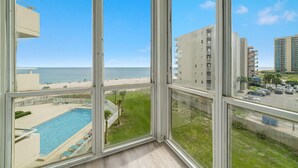 A large window with a view of a swimming pool, a beach, and adjacent buildings. - Perdido Sun 416 (Pensacola)