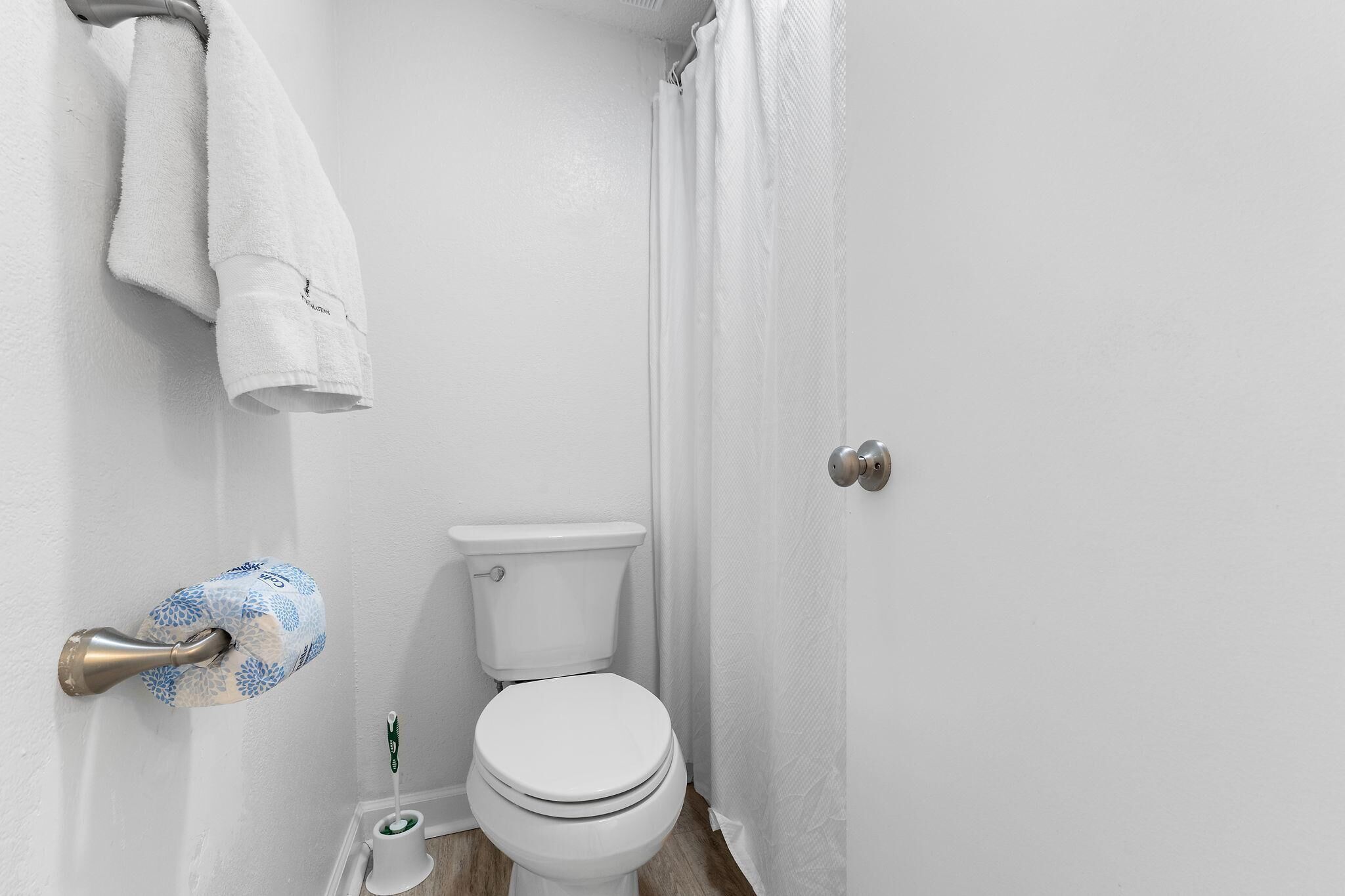 A bathroom with a toilet, a towel rack, and a toilet paper holder.