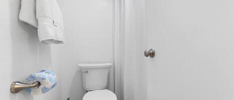A bathroom with a toilet, a towel rack, and a toilet paper holder.