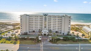 Un hotel moderno de muchas plantas, con entrada principal y vistas a la playa y el océano.
