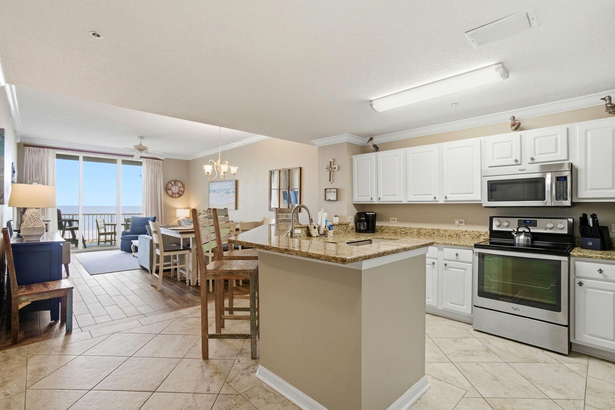 A modern kitchen with white cabinets, stainless steel appliances, and a central island.