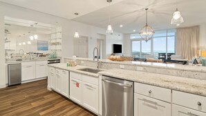 A modern kitchen with a large island, stainless steel appliances, and pendant lighting. - Vista Del Mar 402 (Pensacola)