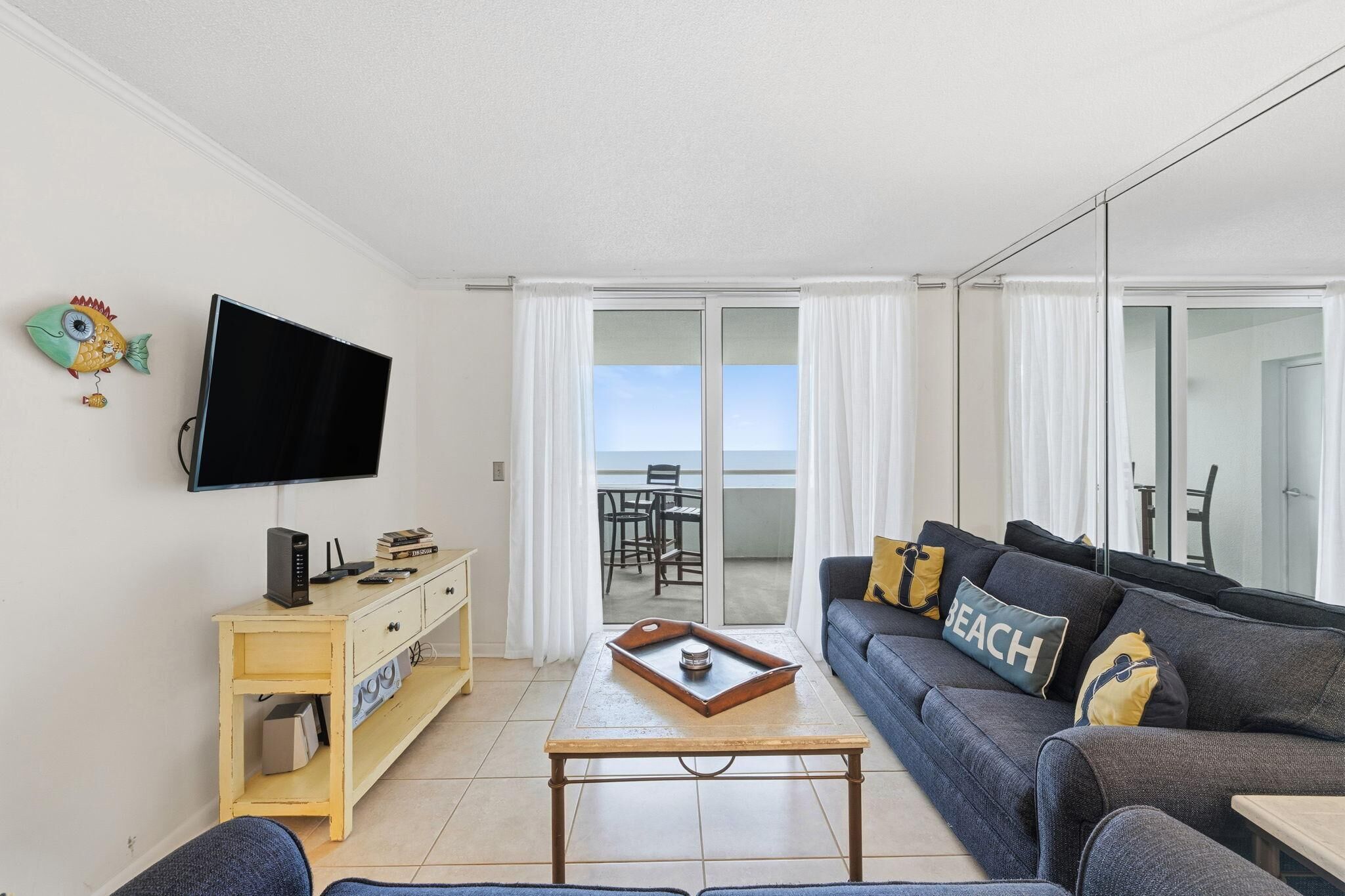 Un soggiorno moderno con divano, tavolino, televisore e un balcone con vista.