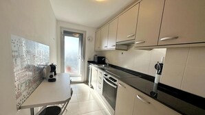 A compact kitchen with a dining area, featuring a small table, a chair, and a window with a view. - Seaside Getaway: Spacious Apartment with Terrace, Pool & Parking in Salou (Salou)