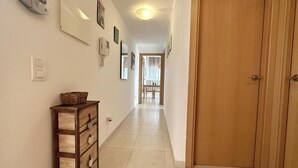 A hallway with a wooden door, a wall-mounted air conditioner, and a small wooden cabinet with drawers. - Seaside Getaway: Spacious Apartment with Terrace, Pool & Parking in Salou (Salou)