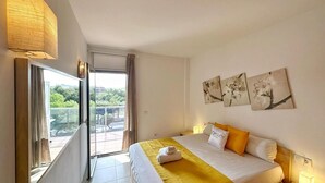 A hotel room with a bed, a balcony, and a view of greenery. - Seaside Getaway: Spacious Apartment with Terrace, Pool & Parking in Salou (Salou)