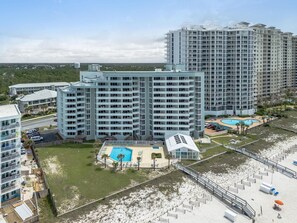 A high-rise hotel with multiple balconies, a swimming pool, and a beach area. - Perdido Sun 702 (Pensacola)