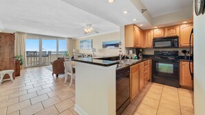 A spacious kitchen with a large island, wooden cabinets, and a view to the outside. - Perdido Sun 702 (Pensacola)