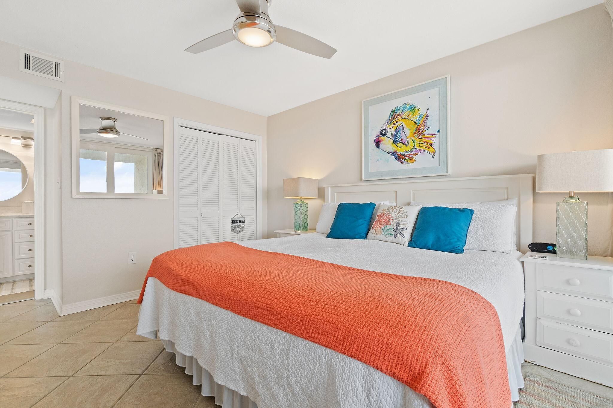 A bedroom with a bed, a ceiling fan, a window, and a painting on the wall.