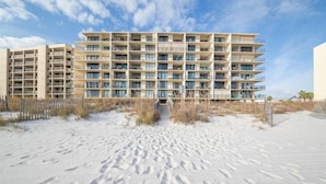 A multi-story hotel with balconies, located on a sandy beach. - Lei Lani 607t (Orange Beach)