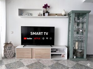 Ein modernes Wohnzimmer mit einem Flachbildfernseher, einer Bücherwand und einer Vitrine mit Geschirr.
