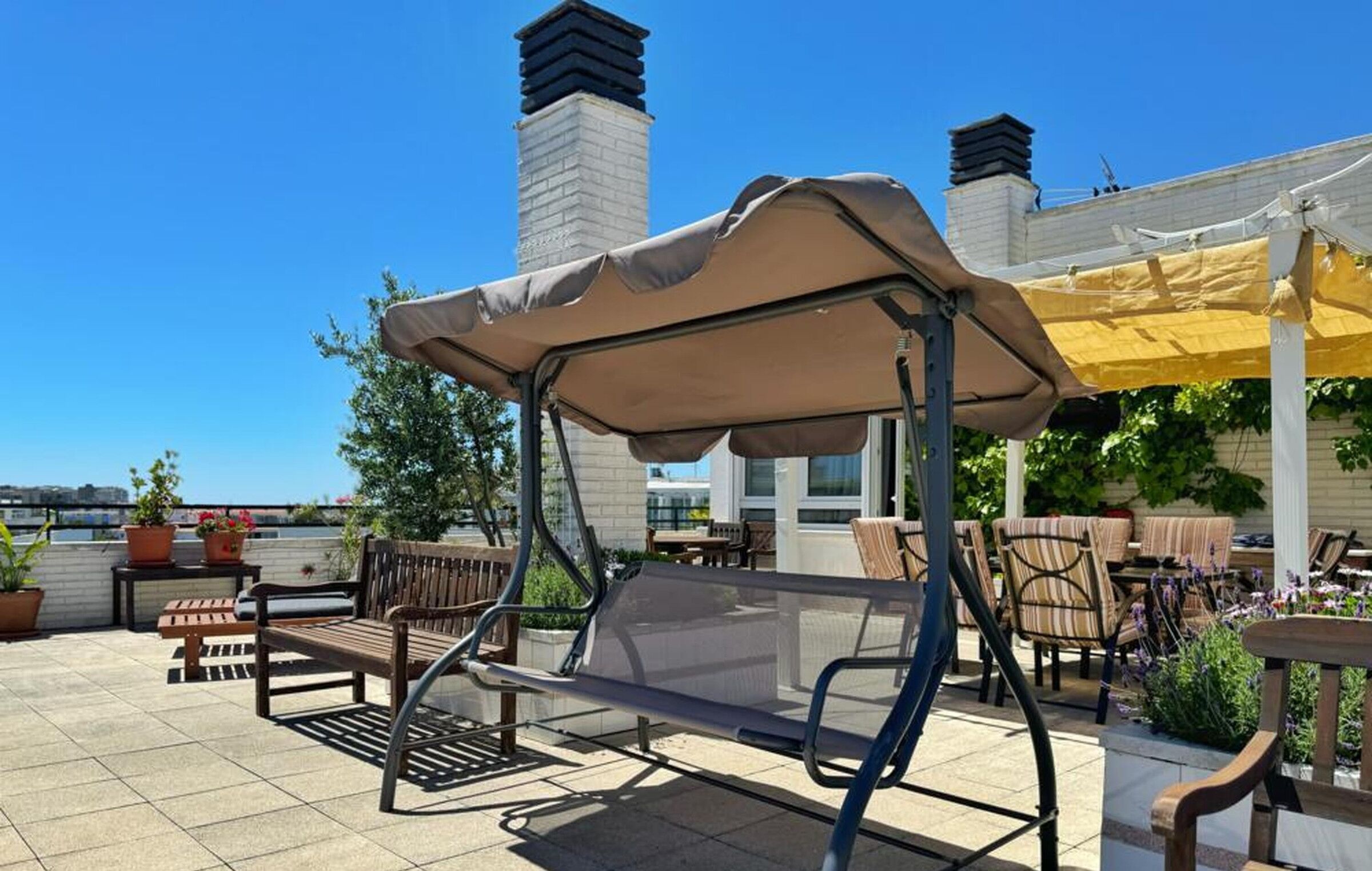 A patio with a swing seat, outdoor seating, and a view of the city skyline.