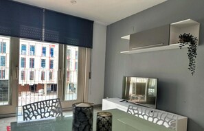 Enjoy a view of the city from the large window in this stylish living room, featuring a flat-screen TV and dining area.