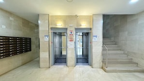 A lobby with a double elevator, a staircase, and a security desk with a metal barrier. - Cozy Apartment with Pool, 300m from Levante Beach, Free WiFi, Near Port Aventura (Salou)