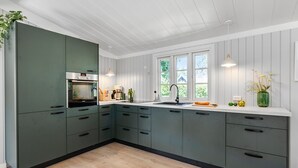 A modern kitchen with a built-in oven, a sink, and a window providing natural light.