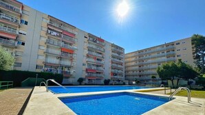 A residential building with a swimming pool, balconies, and a clear sky. - Cozy Apartment with Garden, Pool & Parking - Steps from Playa del Llevant! (Salou)
