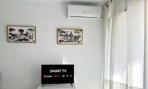 A room with a wall-mounted air conditioner, two framed artworks, and a smart TV displaying streaming services. - Family-Friendly Apartment with WiFi, AC, 500m to Beach, Near Port Aventura (Salou)