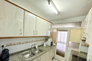 A kitchen with white cabinets, a granite countertop, a sink, a microwave, and a refrigerator. - Family-Friendly Apartment with WiFi, AC, 500m to Beach, Near Port Aventura (Salou)