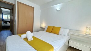 Una habitación de hotel con una cama, un armario de madera, una mesita de noche con lámpara y una ventana.