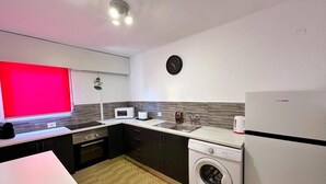 Une cuisine compacte équipée d’un four à micro-ondes, d’un évier et d’un lave-linge.
