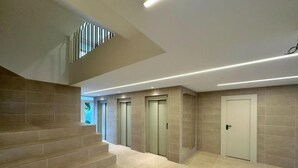 Un interno moderno con una scala che conduce a un piano superiore, una fila di ascensori e una porta.