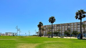 Un edificio ampio con tetto piatto e numerose finestre, immerso in un'area verde con palme.