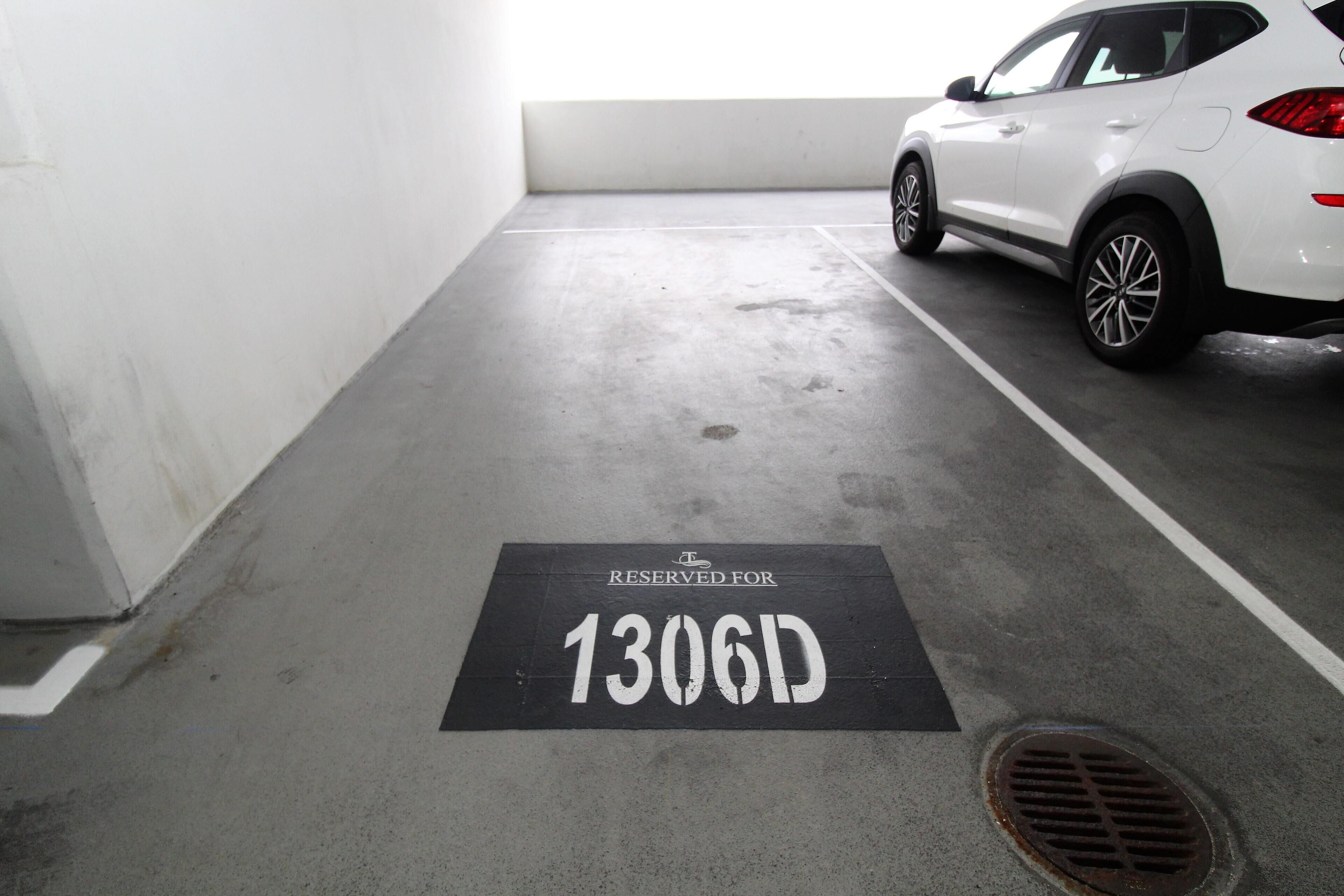 A parking space marked with "RESERVED FOR 1306D" in a parking garage.