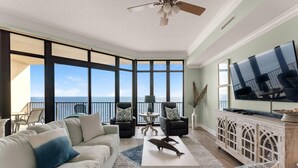 A spacious living room with a large TV, comfortable seating, and a view of the ocean. - Phoenix West 1508 (Orange Beach)