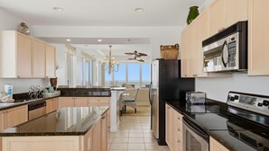 A modern kitchen with a central island, a built-in oven, and a microwave. - La Playa 801 (Pensacola)