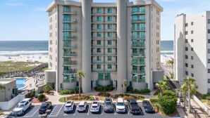 Ein mehrstöckiges Hotel mit Pool, Parkplatz und Meerblick.