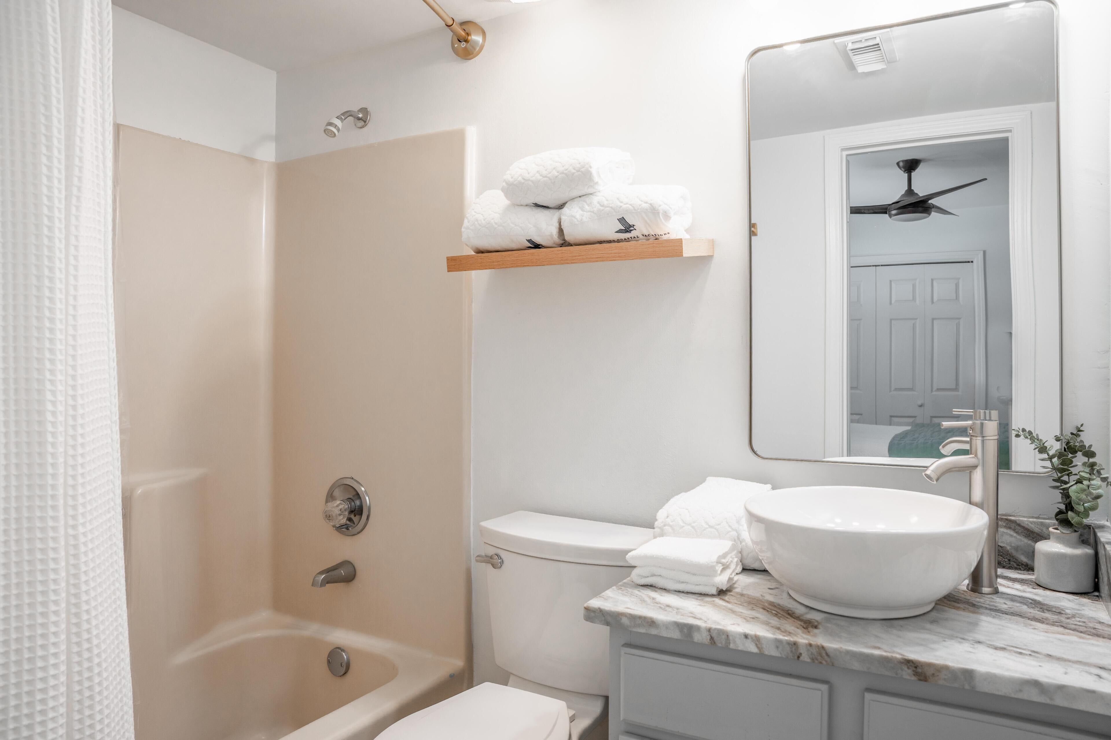 A bathroom with a bathtub, toilet, and a vanity with a sink.