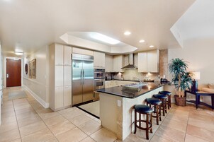 A modern kitchen with a central island, stainless steel appliances, and a bar area with stools.