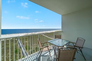A balcony with a glass table and chairs overlooking a beach. - Tidewater 503 (Orange Beach)