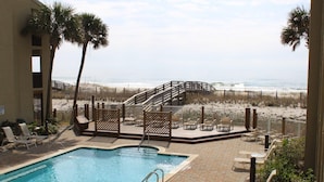 A pool area with lounge chairs and a wooden deck overlooking the beach. - Shipwatch A403 (Pensacola)